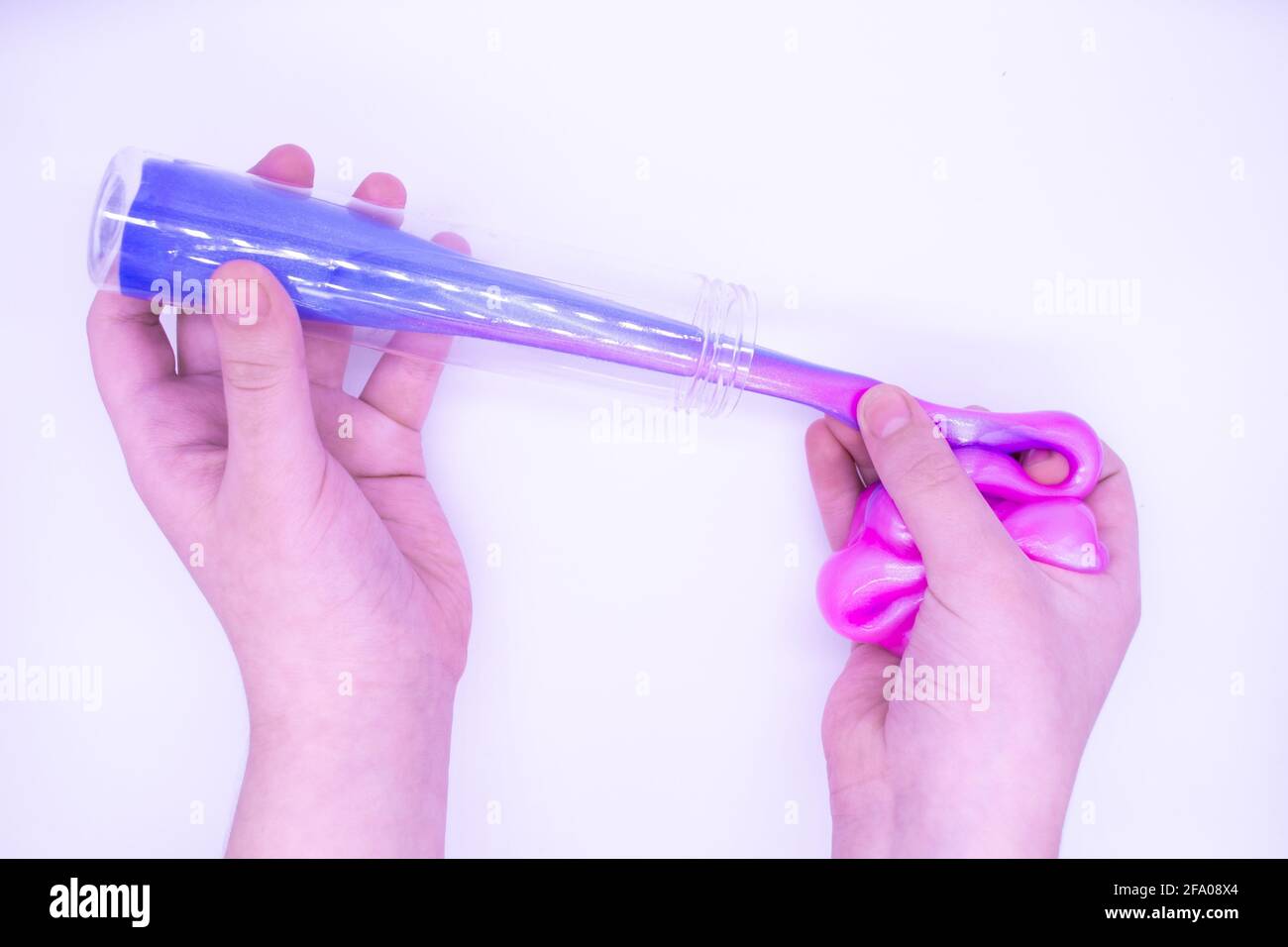 Hands pull out of transparent tube two-tone pink-and-blue slime. Stock Photo