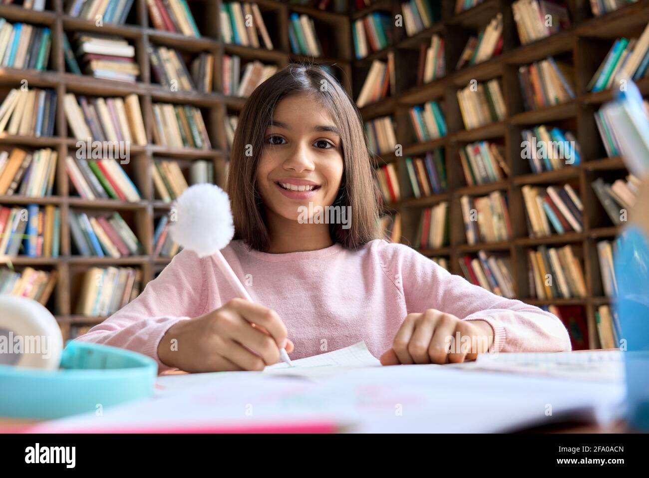 Portrait of happy Mexican teen student girl sitting at table camera looking. Stock Photo