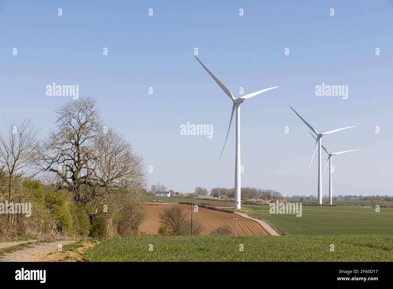 Crick, Northamptonshire, UK - April 19th 2021: Three wind turbines stand in arable farmland beneath a clear blue sky. Stock Photo