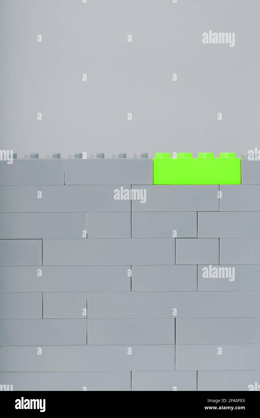 A wall made of children's construction kit parts with bright green bricks. Concept Stock Photo