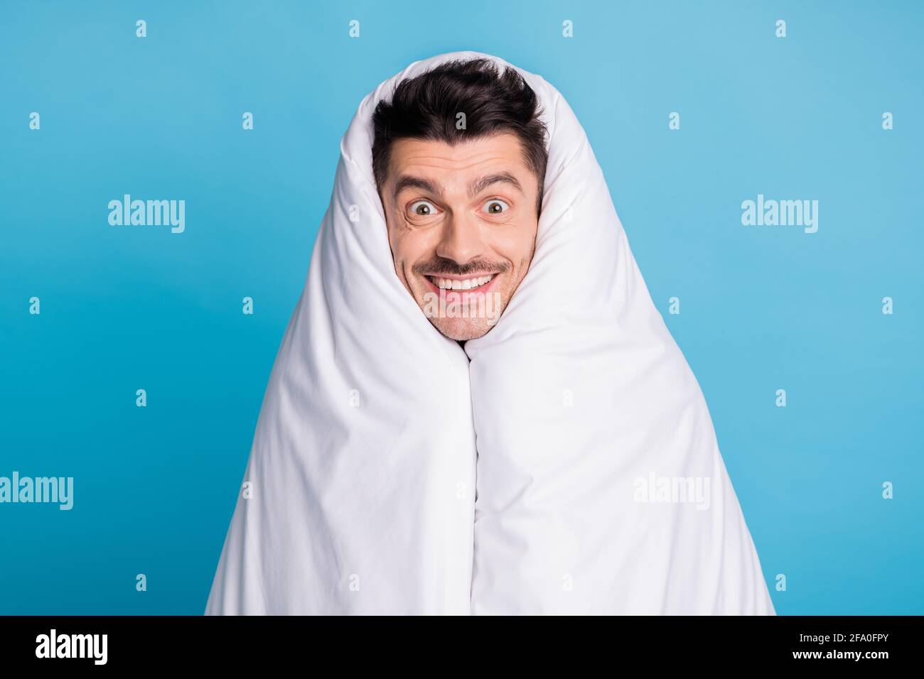 Photo portrait of positive smiling guy wrapped in blanket isolated on