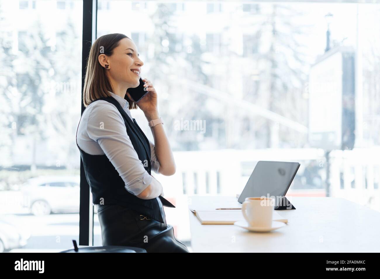Young charming woman calling with smartphone while sitting alone in ...