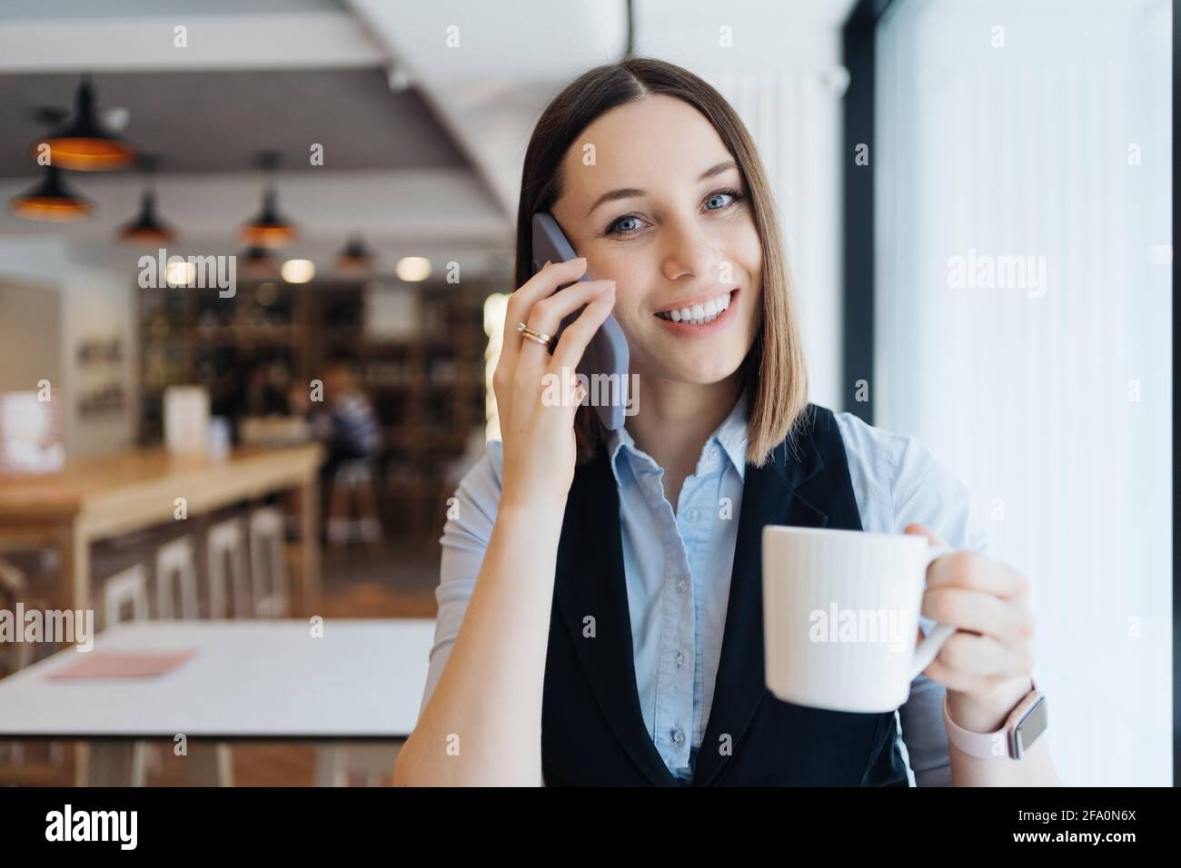 Young charming woman calling with smartphone while sitting alone in ...