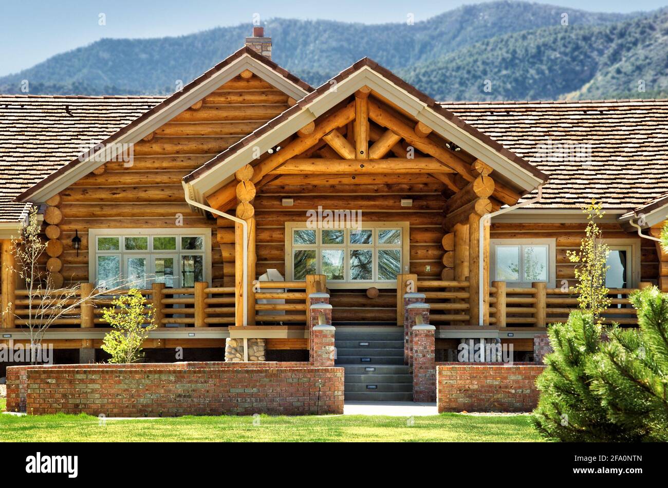 A exterior view of a modern log cabin, with a patio area, and contemporary landsaping. Stock Photo