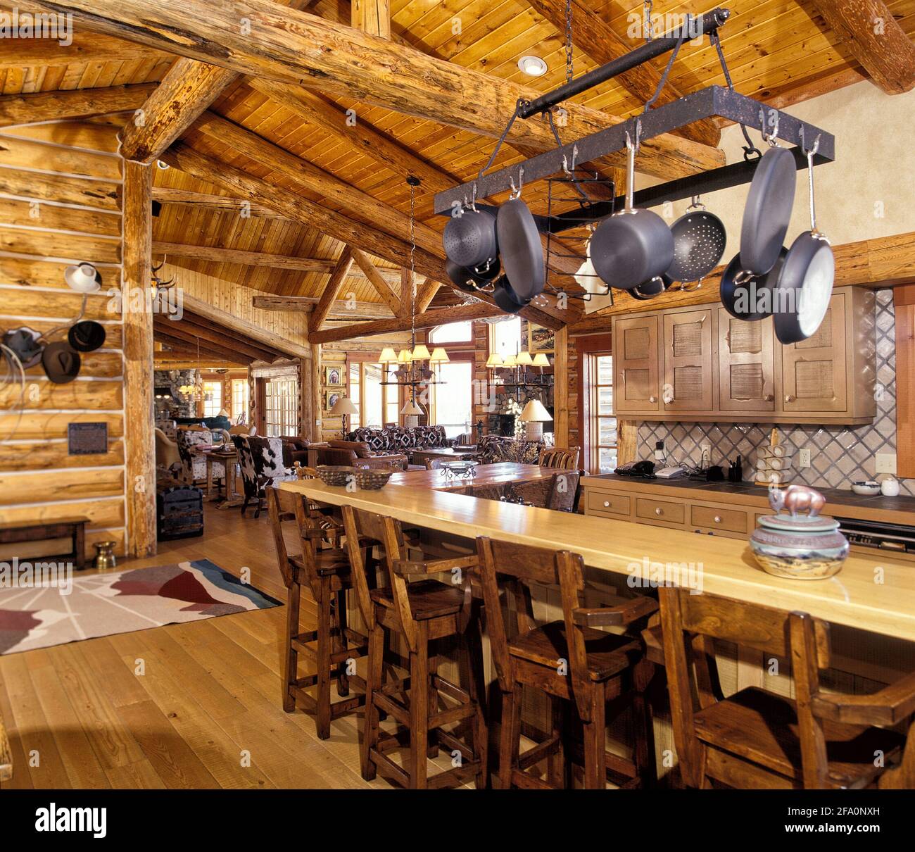 The kitchen with bar counter, pot rack, and rustic cabinetry, in a modern log cabin in the mountains Stock Photo
