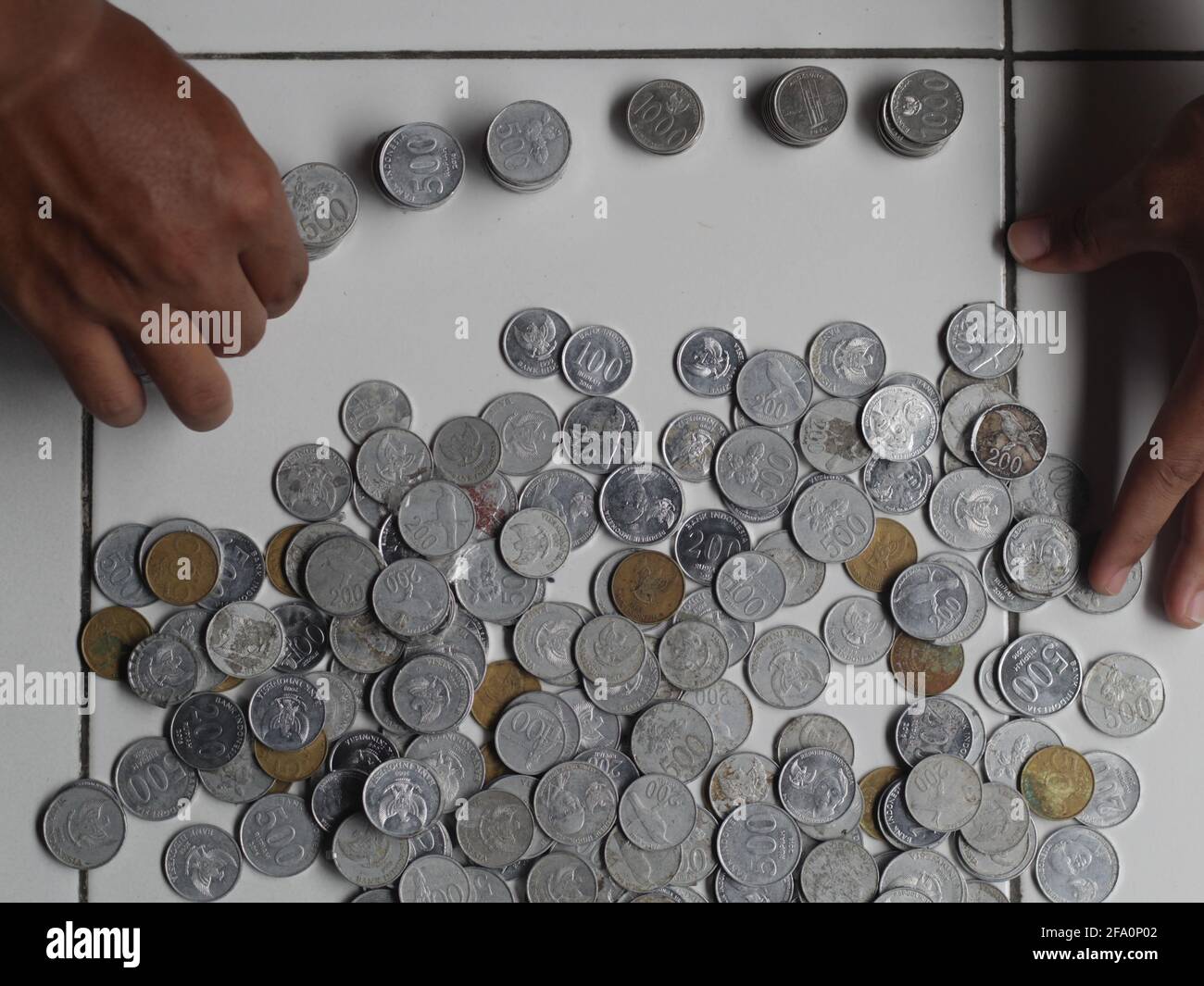 Man counting indonesian penny. Stacked Rupiah coin. Stock Photo