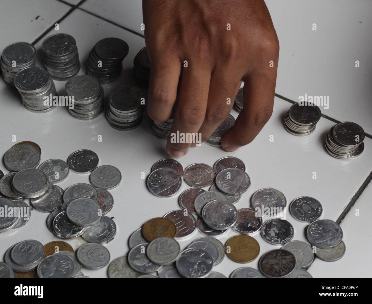 Man counting indonesian penny. Stacked Rupiah coin. Stock Photo