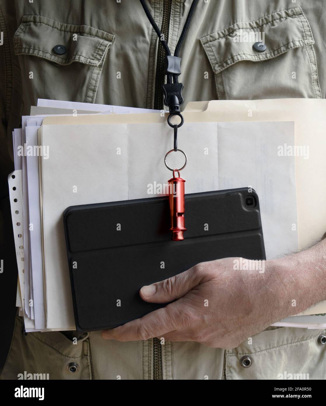 A man's hand carrying documents and an electronic tablet. From his neck hangs a red whistle, he is a wistle blower. Stock Photo