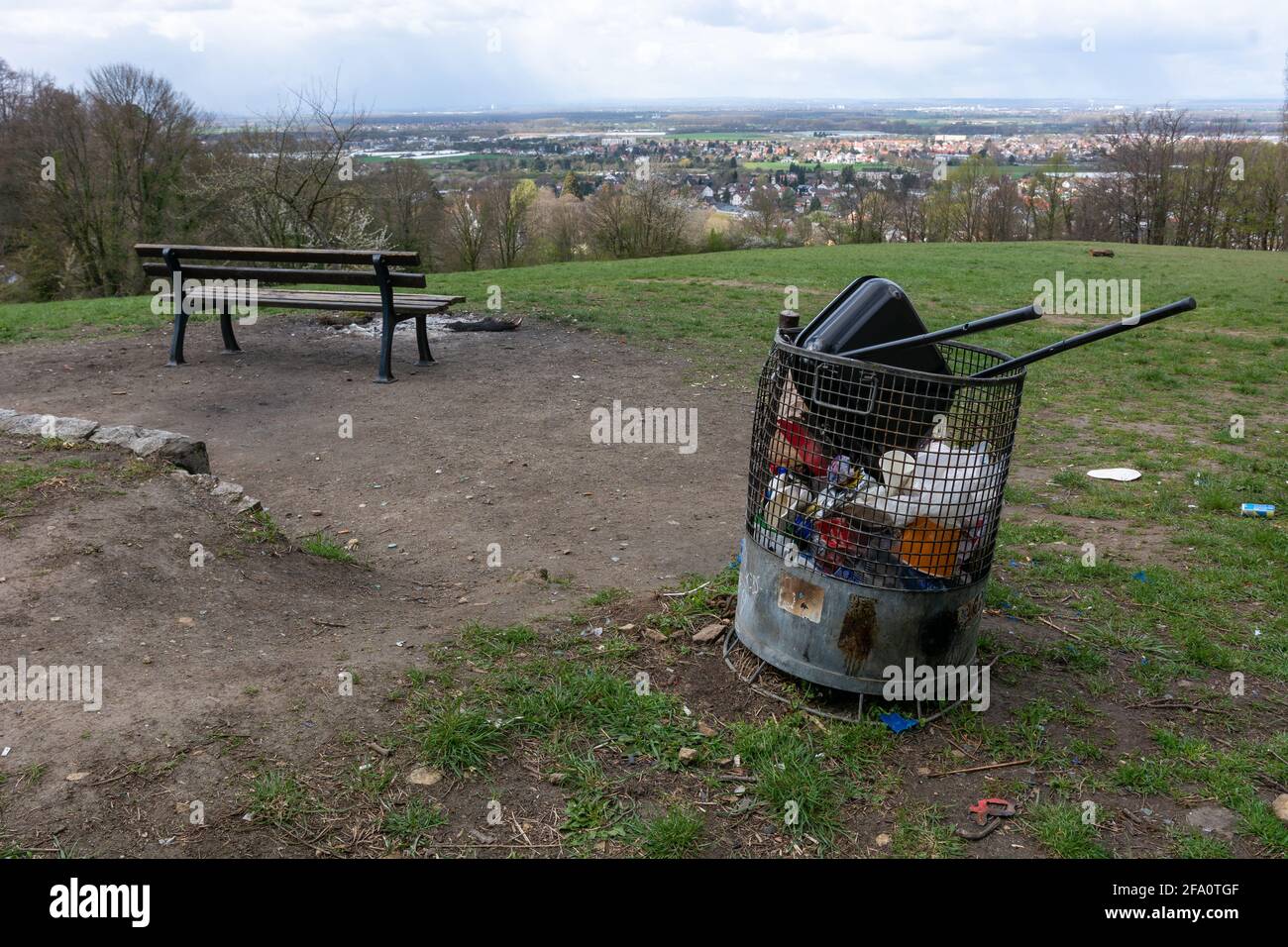 Full trash can next to a bench with fantastic view above Jugenheim near Darmstadt, Hessen. Trash can with waste and broken grill after fire and grill Stock Photo