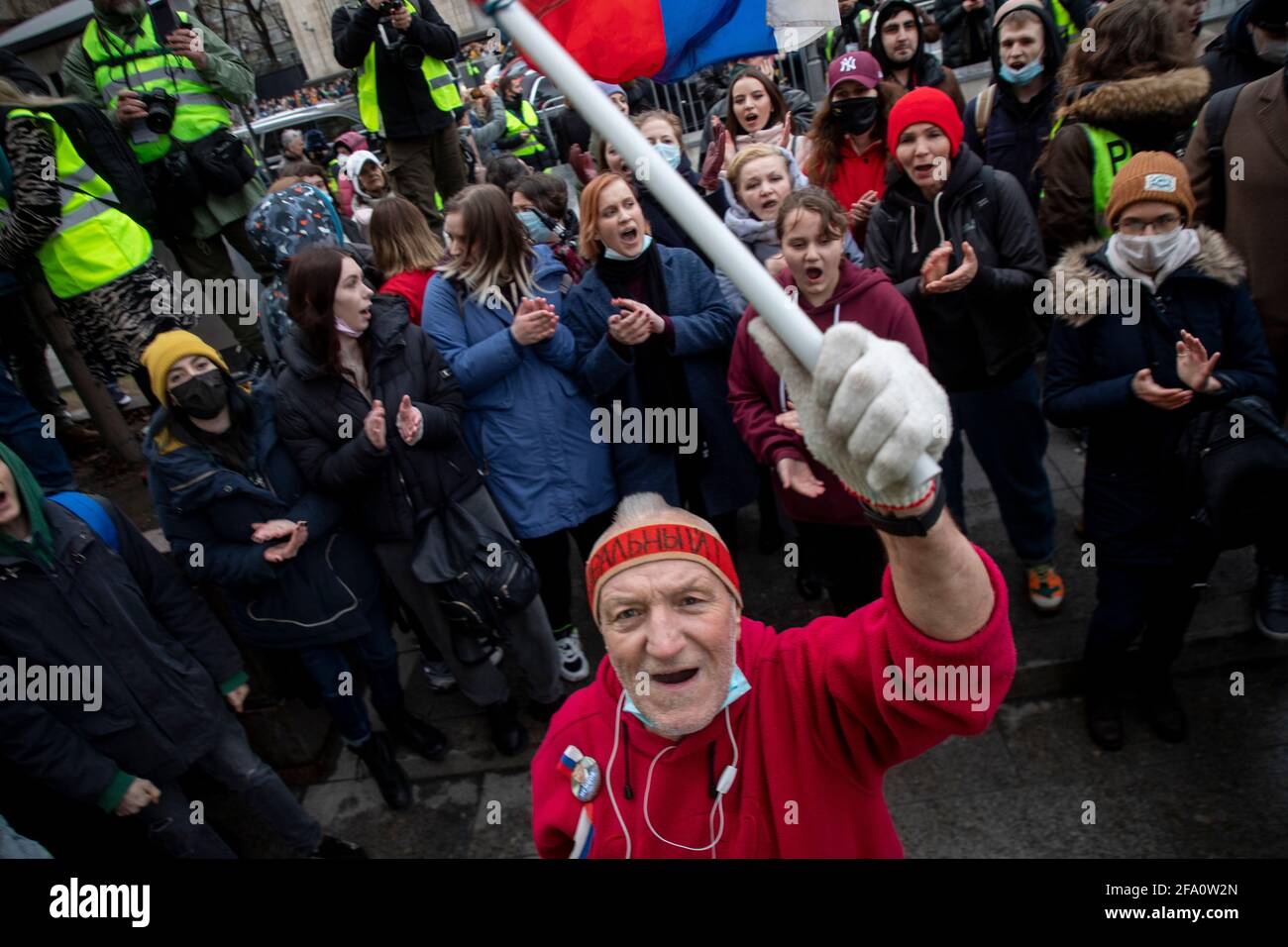Moscow, Russia. 21st of April, 2021 An opposition supporter waves a Russian national flag as he walks in a street during a rally in support of jailed Kremlin critic Alexei Navalny, in central Moscow, Russia. Jailed Kremlin critic Alexei Navalny's team called for demonstrations in more than 100 cities, after the opposition figure's doctors said his health was failing following three weeks on hunger strike. Stock Photo