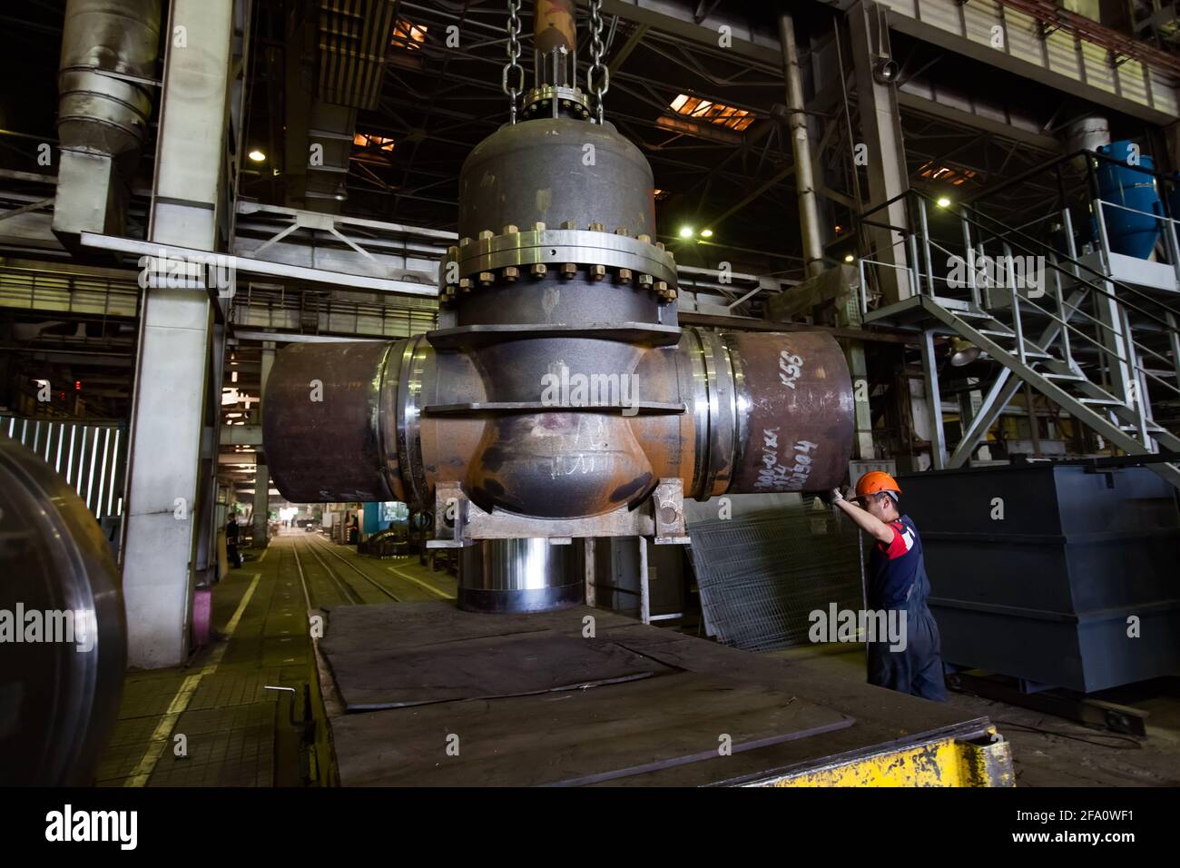 Worker loading giant valve on rail platform. Oil and gas industry shut ...
