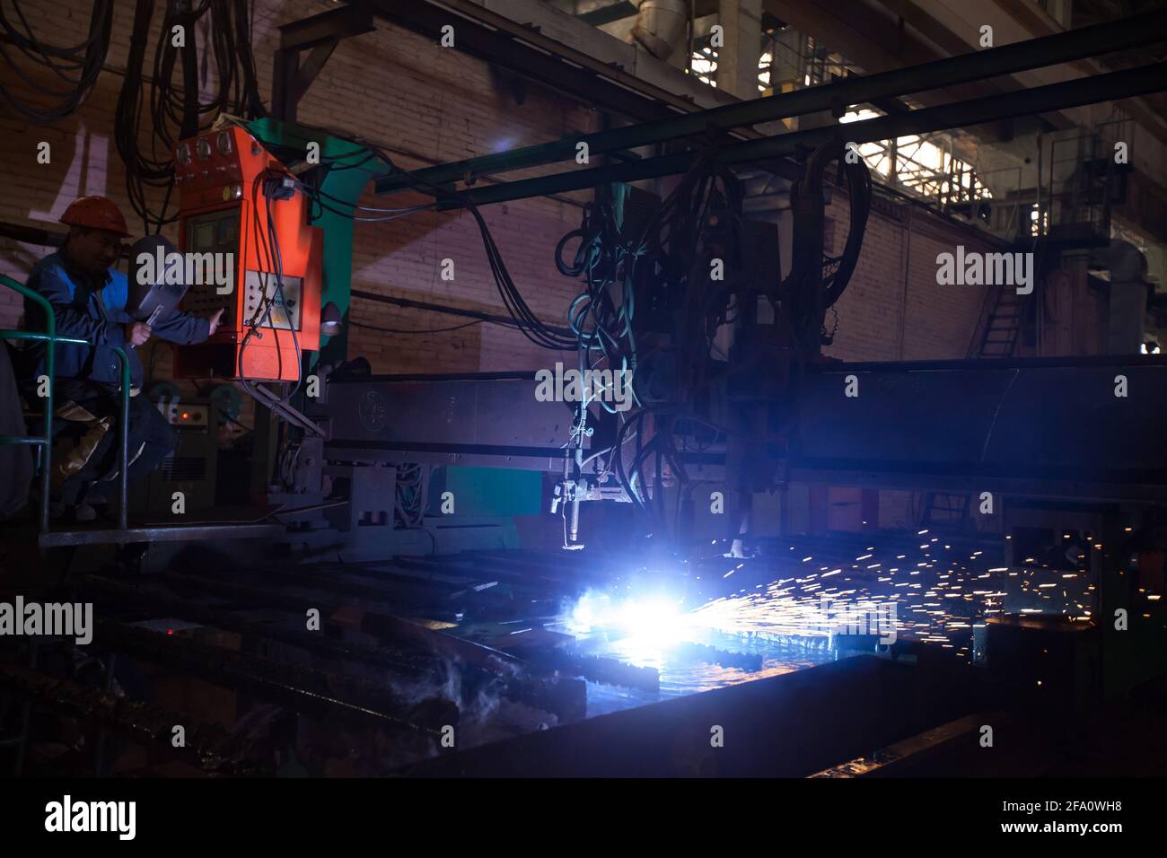 Ust'-Kamenogorsk,Kazakhstan:Vostokmashzavod factory.Heavy engineering plant workshop.Asian operator (left) controls welding machine (right). Stock Photo