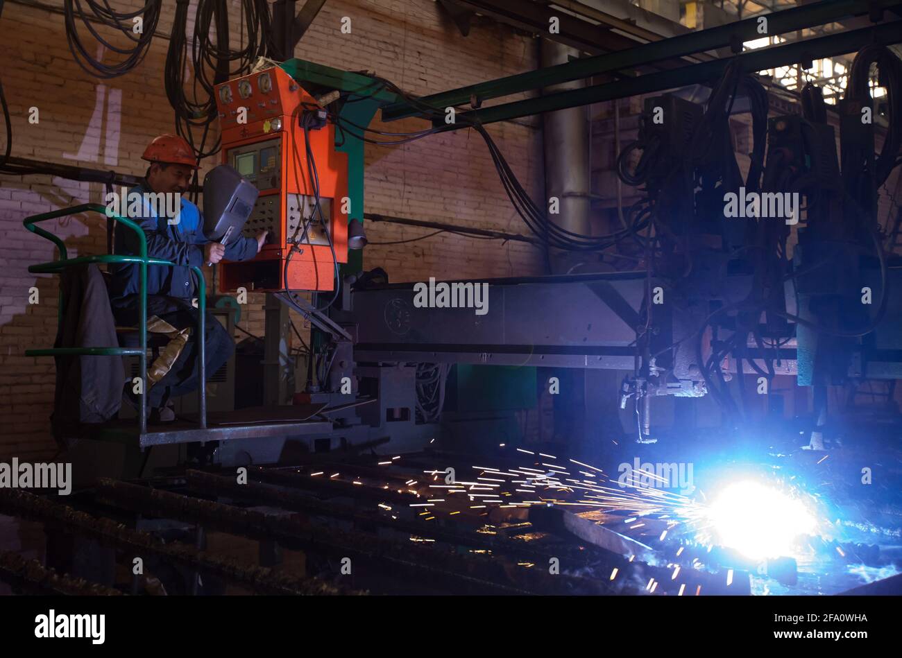 Ust'-Kamenogorsk, Kazakhstan: Vostokmashzavod factory. Heavy engineering plant workshop. Asian operator (left) controls welding machine. Stock Photo