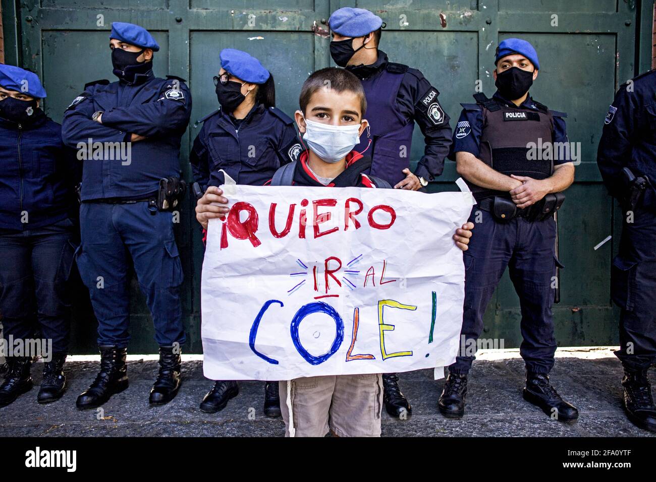 Buenos Aires, Federal Capital, Argentina. 21st Apr, 2021. A boy holds a banner that reads, ''I want to go to Cole, '' and behind him police officers guard the gates of the Presidential Residence. With Argentina's schools closed, a group of parents organized a class in front of the President's Residence in protest against the suspension of classroom attendance for 15 days, a measure that President Alberto Fernandez ordered last Wednesday through a Decree of Necessity and Urgency to contain the resurgence of Covid-19 in the country. Credit: Roberto Almeida Aveledo/ZUMA Wire/Alamy Live News Stock Photo