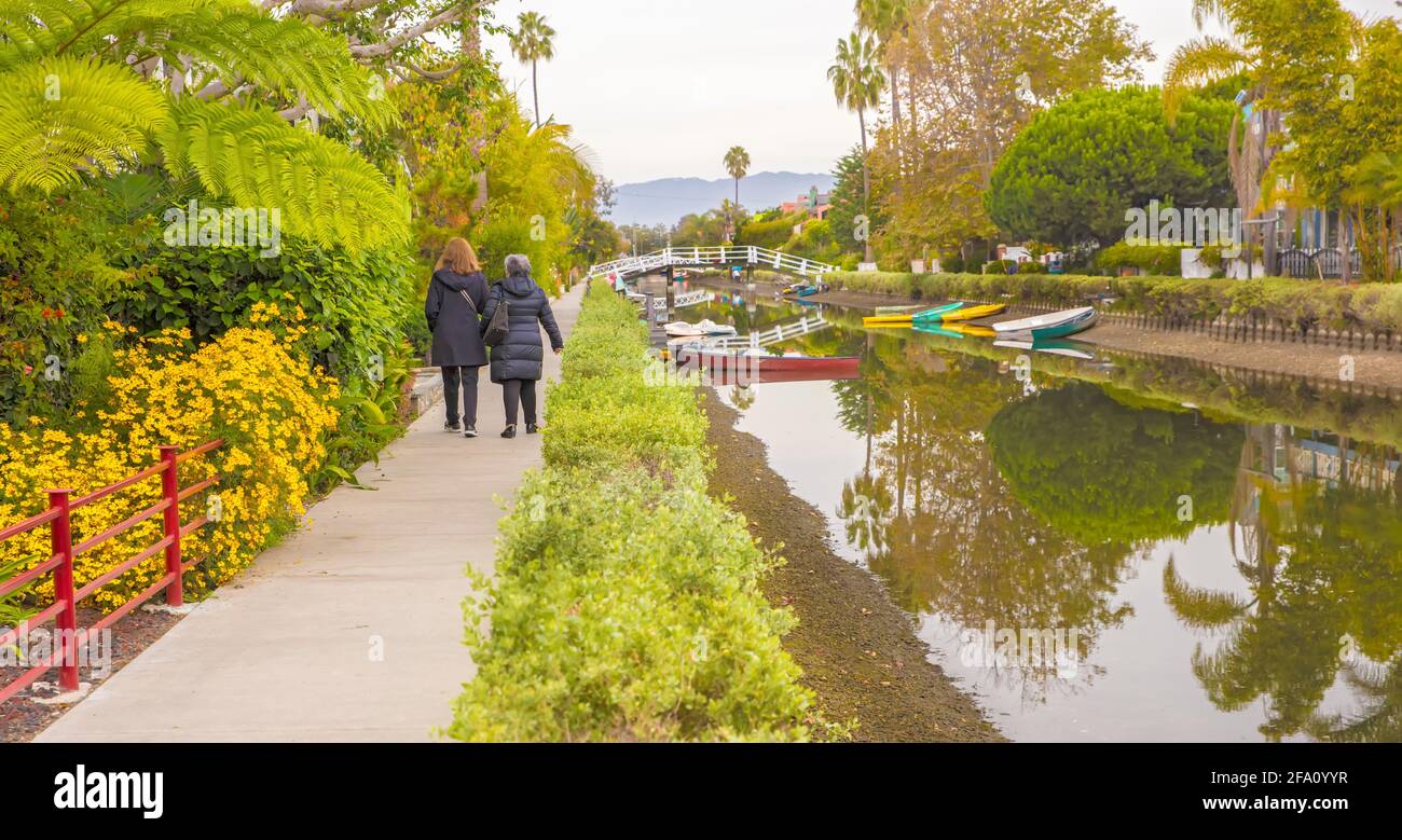 Back view of two women walking along canal in Venice Beach, Los Angeles, California, USA Stock Photo