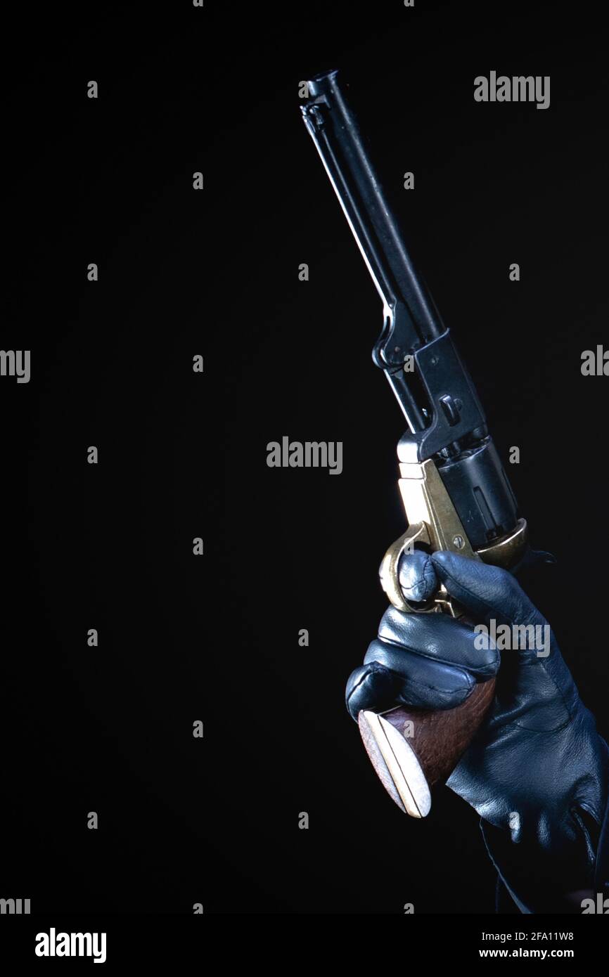 humans hand in black glove with revolver on black background Stock ...