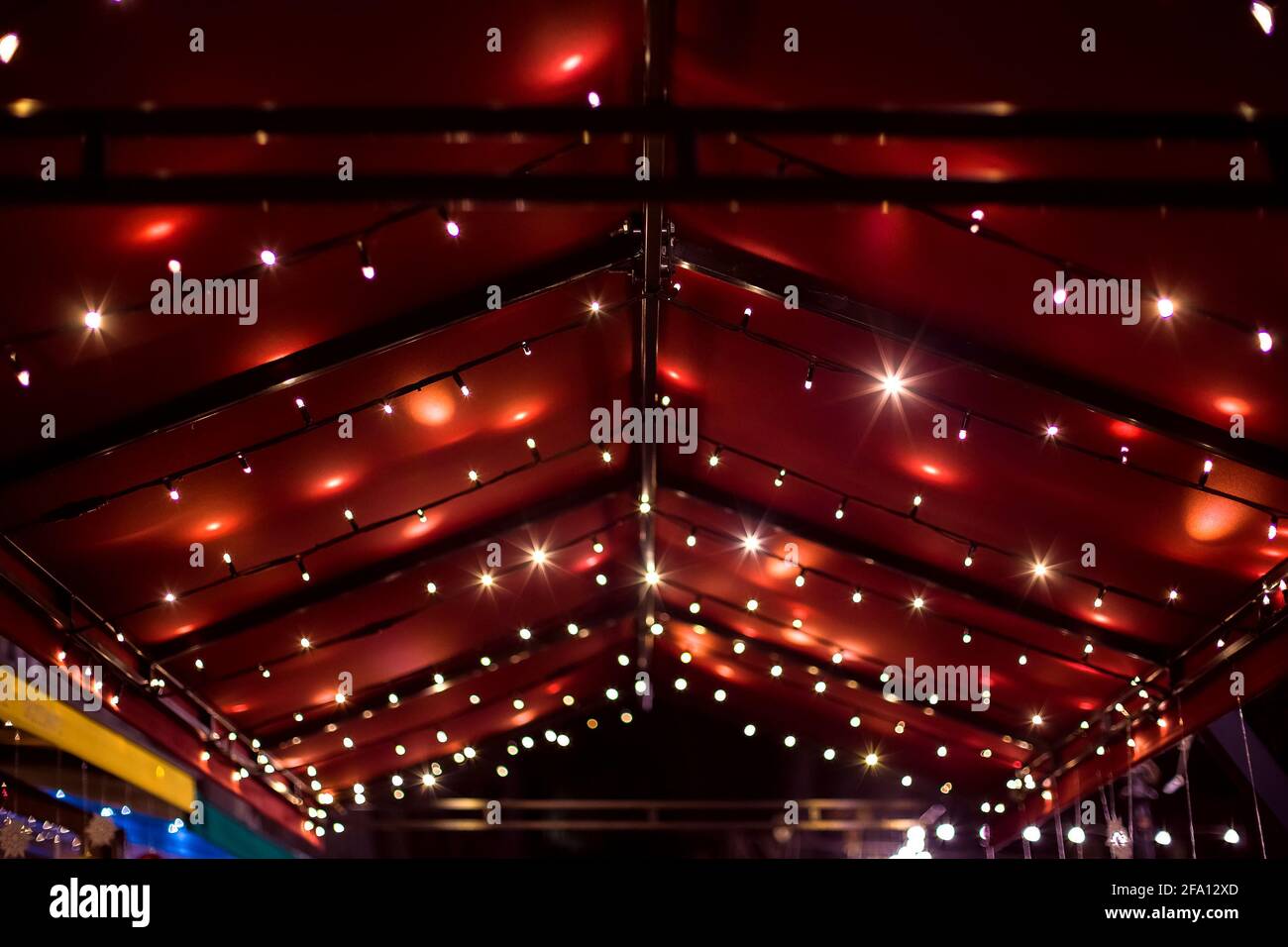 top of the canopy in a red textile gazebo with string light garlands ...