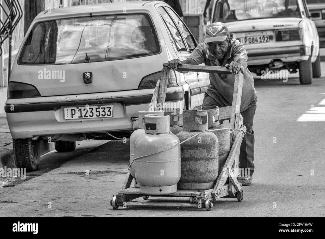 Cuban senior man pushing car with natural gas cylinders, Santiago de Cuba, Cuba Stock Photo