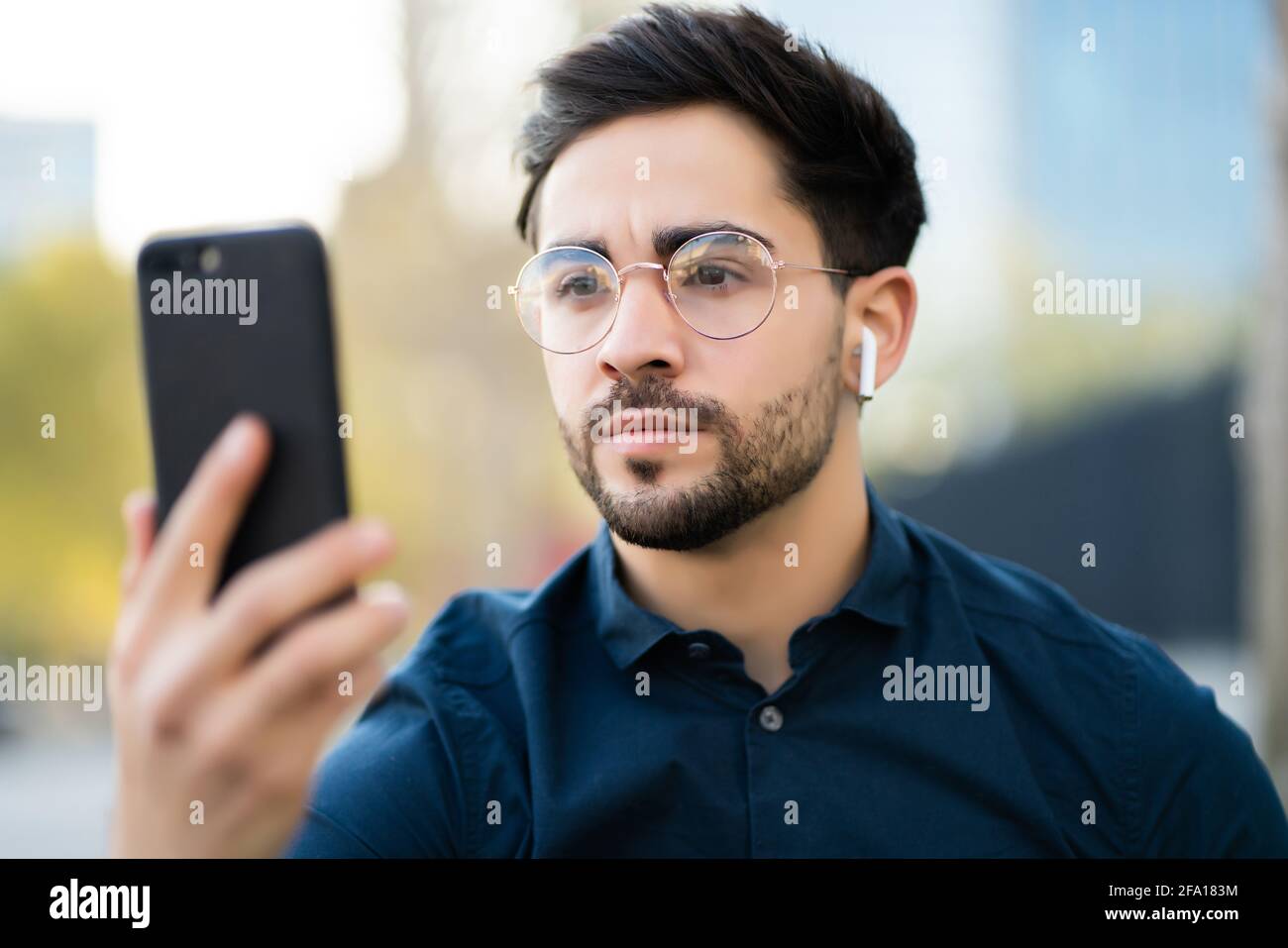 Young man using face id for unlock mobile phone outdoors. Stock Photo