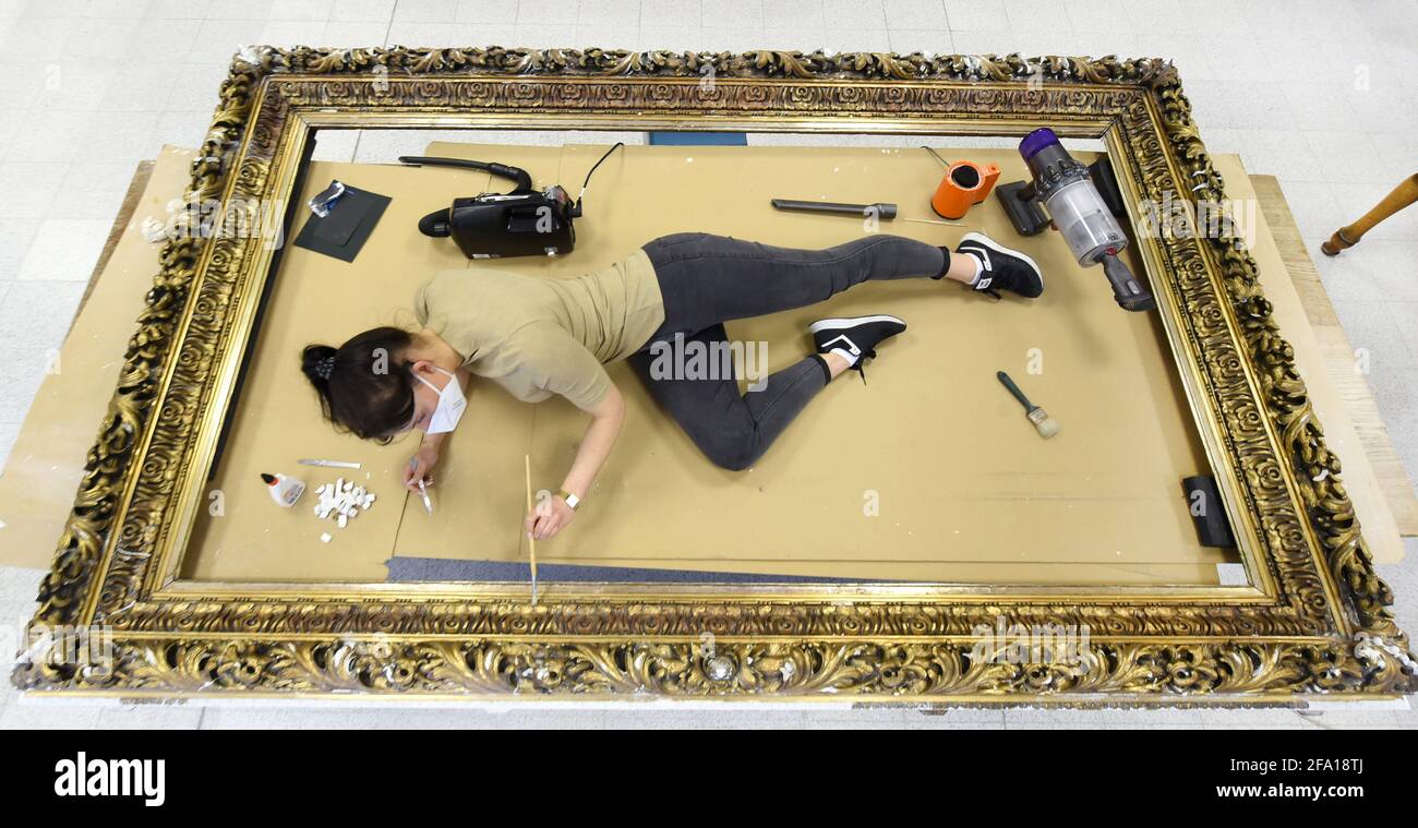 20 April 2021, Thuringia, Altenburg: 22-year-old Milena Leibelt is repairing a richly decorated and gilded 19th-century stucco frame measuring 2.80 by 1.75 in the restoration department of the Lindenau Museum. The work in the museum is part of an Altenburg practical year for art object and monument restoration, which is considered a preparatory internship for university studies in restoration. During their assignment in the restoration department, the participants gain insights into the various focal points of the work of all the restoration institutions involved and, under the guidance of var Stock Photo