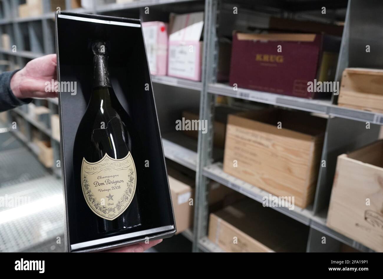 Tornesch, Germany. 21st Apr, 2021. An employee holds a Champagne bottle of "Dom  Perignon Vintage 2008" in an extra warehouse at the IWL (International Wine  Logistics) logistics centre of wine merchant Hawesko.