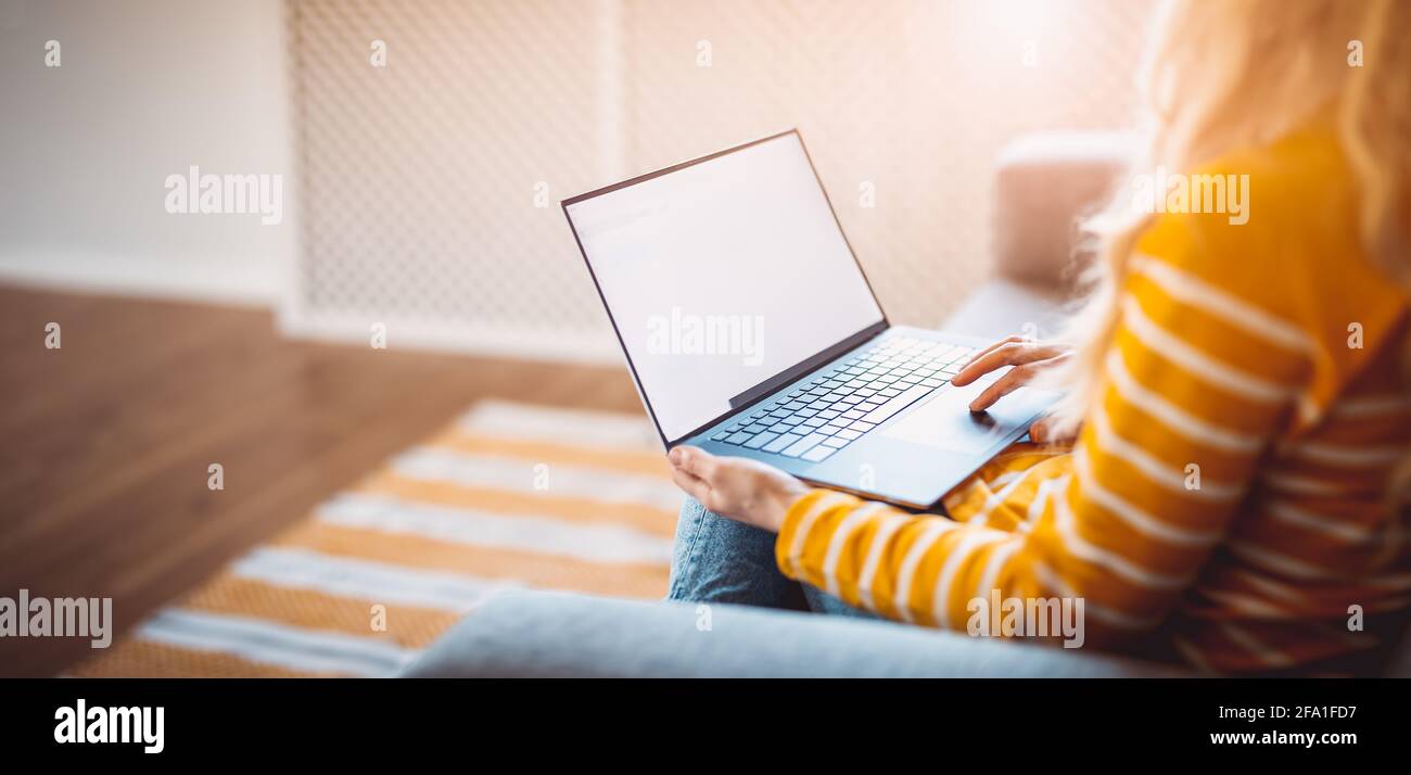 Young woman with laptop sitting on the sofa in living room Stock Photo ...
