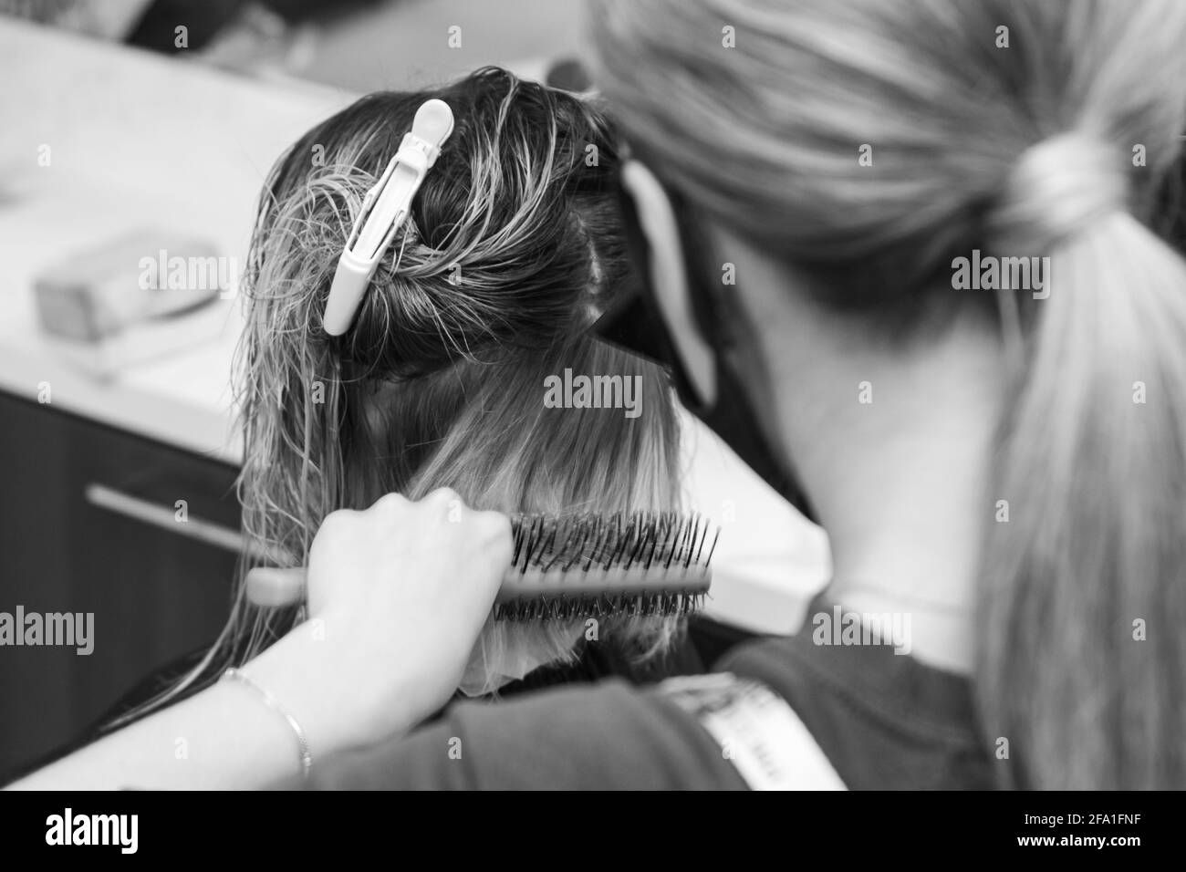 Hairdresser in a mask with at work, drying hair in a client
