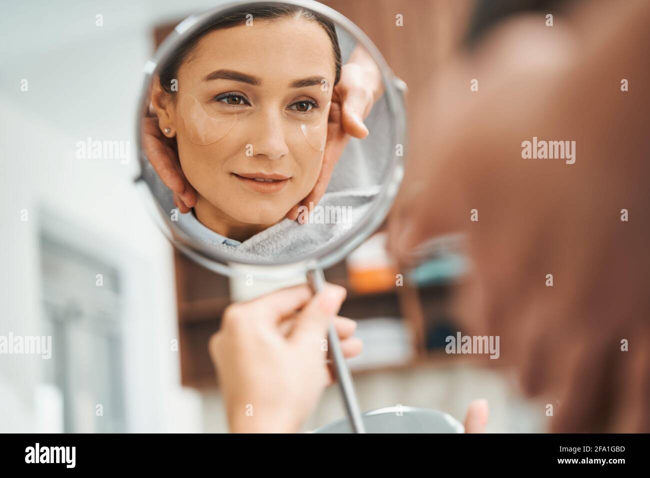 Concentrated lady viewing her reflection in the presence of her cosmetician Stock Photo