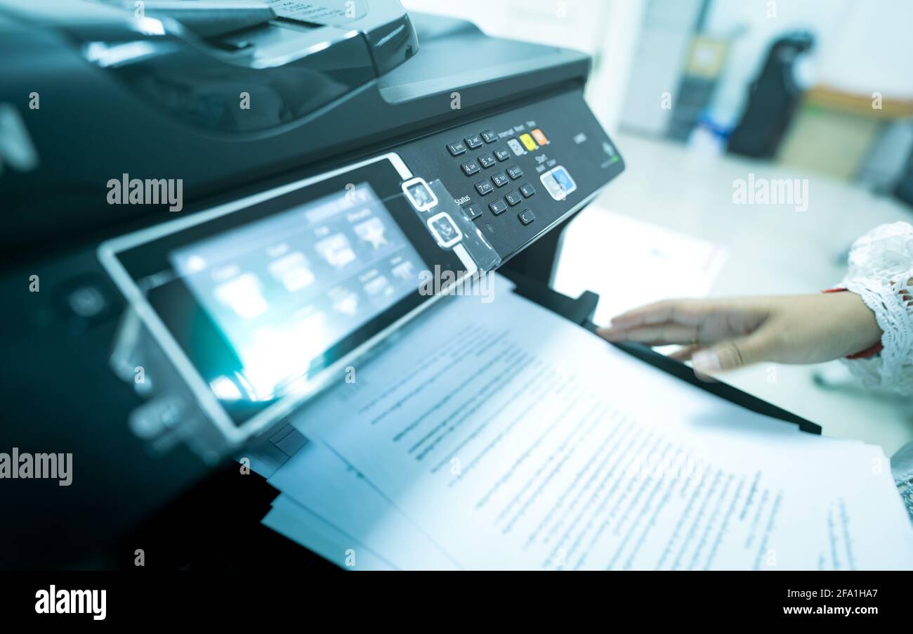 Office worker print paper on multifunction laser printer. Copy, print, scan, and fax machine in office. Modern print technology.  Photocopy machine. Stock Photo