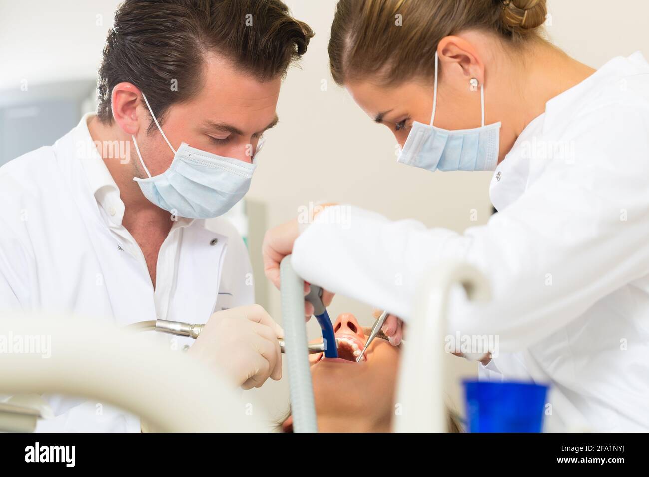 Female patient with dentist and assistant in a dental treatment, wearing masks and gloves Stock