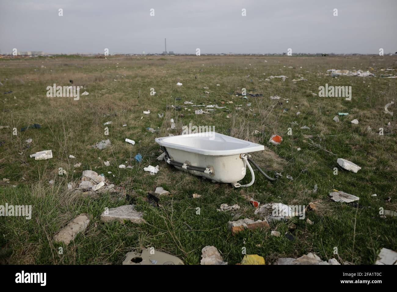 Bucharest, Romania - April 2, 2021: Piles of industrial and home waste lay on a field near inhabited houses. Stock Photo