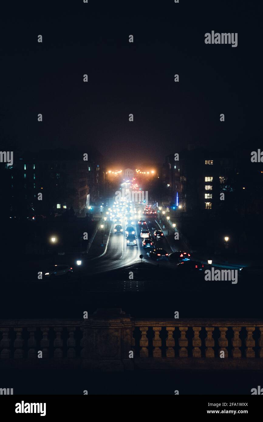 Straight avenue during a rainy night in Munich, Bavaria, Germany. Bridge leads over the Isar (river of Munich). Traffic Lights light up the dark scene Stock Photo