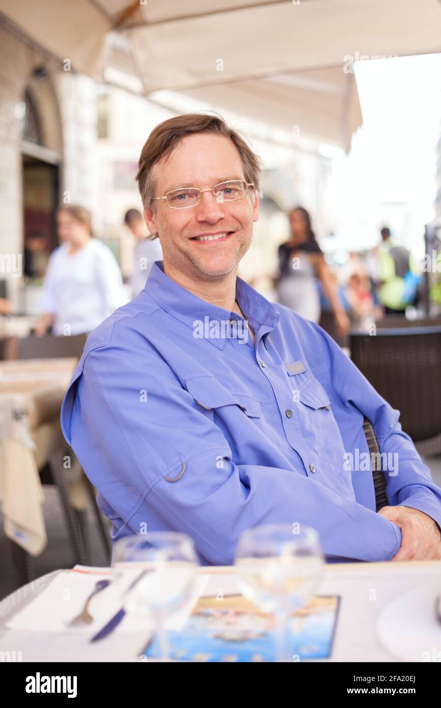 Smiling Caucasian European tourist sitting at Italian outdoor dining restaurant in Rome Stock Photo