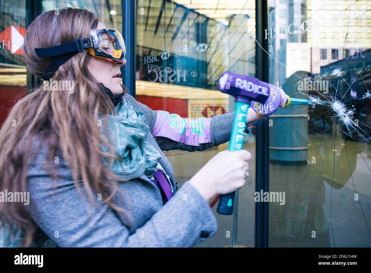 Canary Wharf, London, UK 22nd April 2021 Extinction Rebellion women break windows at HSBC bank as part of a series of actions making up the money rebellion. The environmental group are angry at the bank's 80 billion pound investment in fossil fuels over the past 5 years Stock Photo