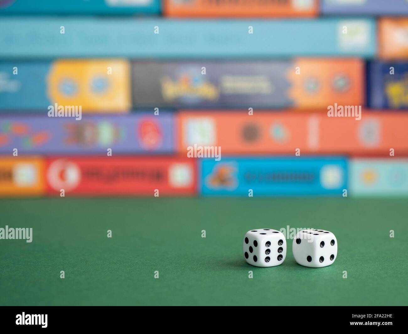 Two dice on the background of board game boxes. Dice games for kids, tweens and adults Stock Photo