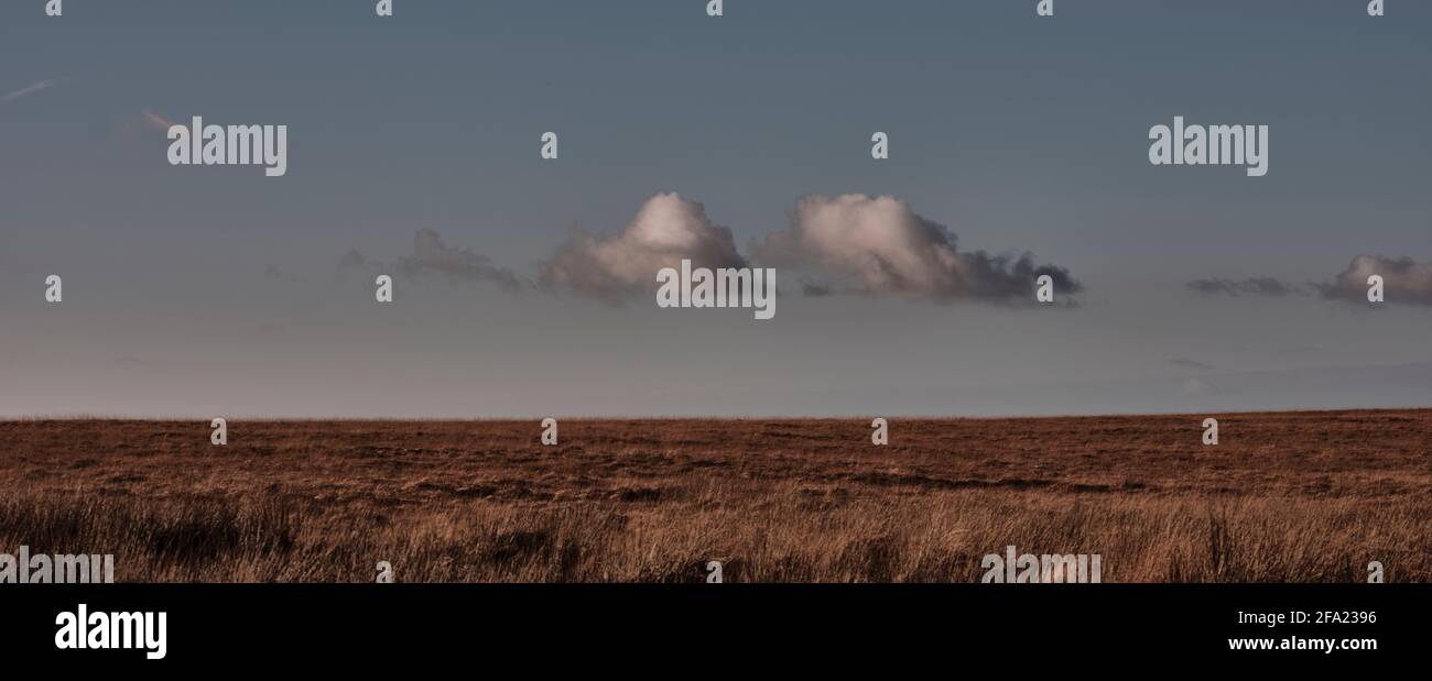 Individual clouds hover above barren landscape on Exmoor, Somerset, UK Stock Photo