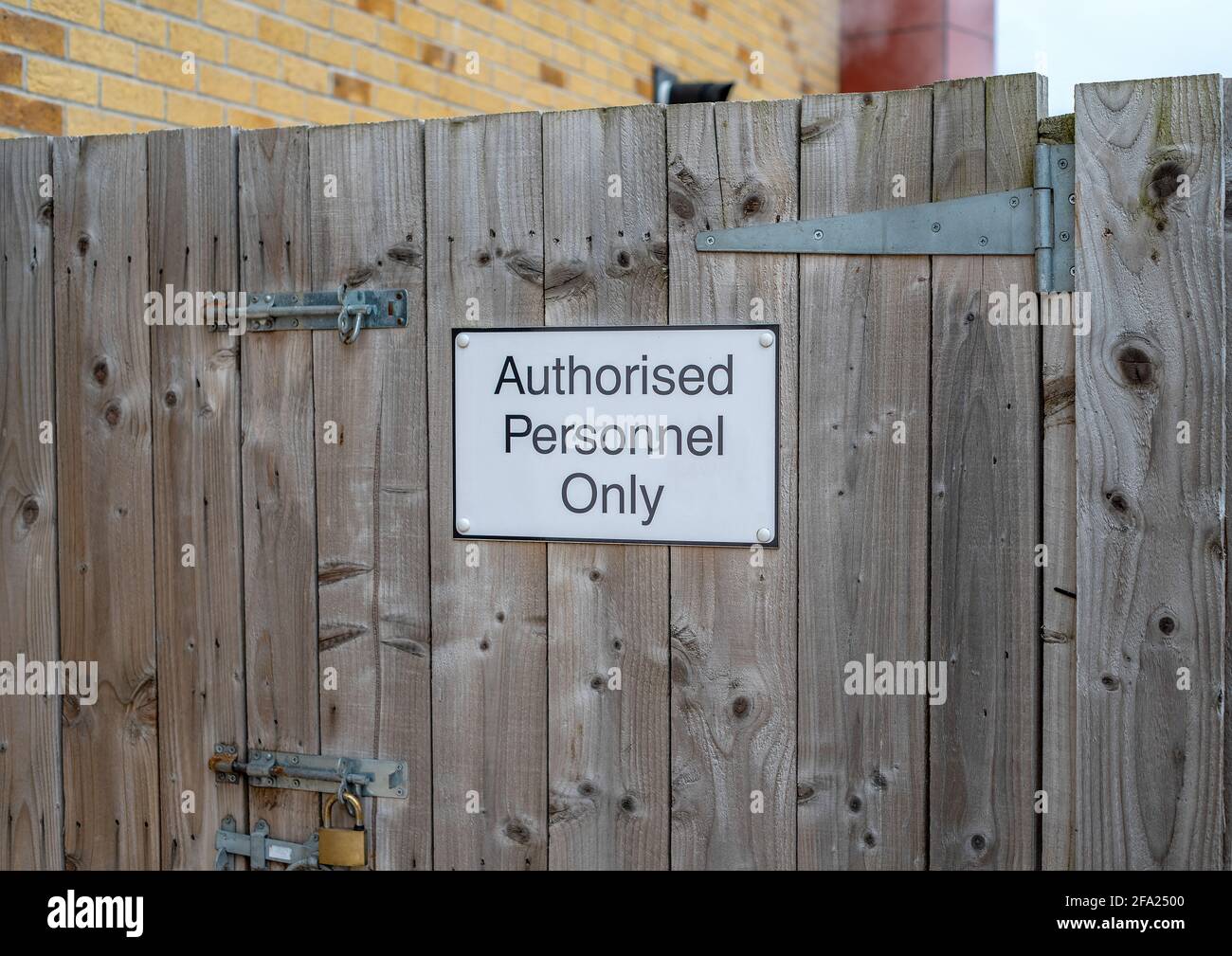Black and white metal sign on a wooden gate with metal hinges and padlock. Stock Photo