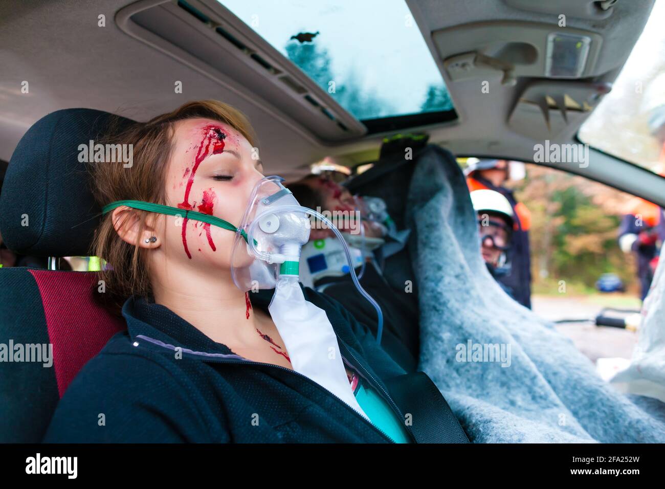 Accident - victim in a crashed vehicle, she receives medical first aid from firefighters Stock Photo
