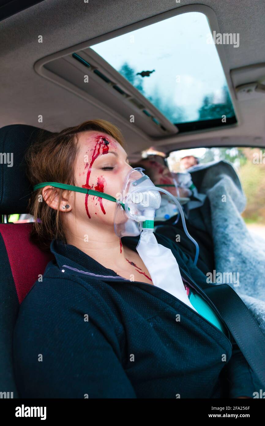 Accident - victim in a crashed vehicle, she receives medical first aid from firefighters Stock Photo