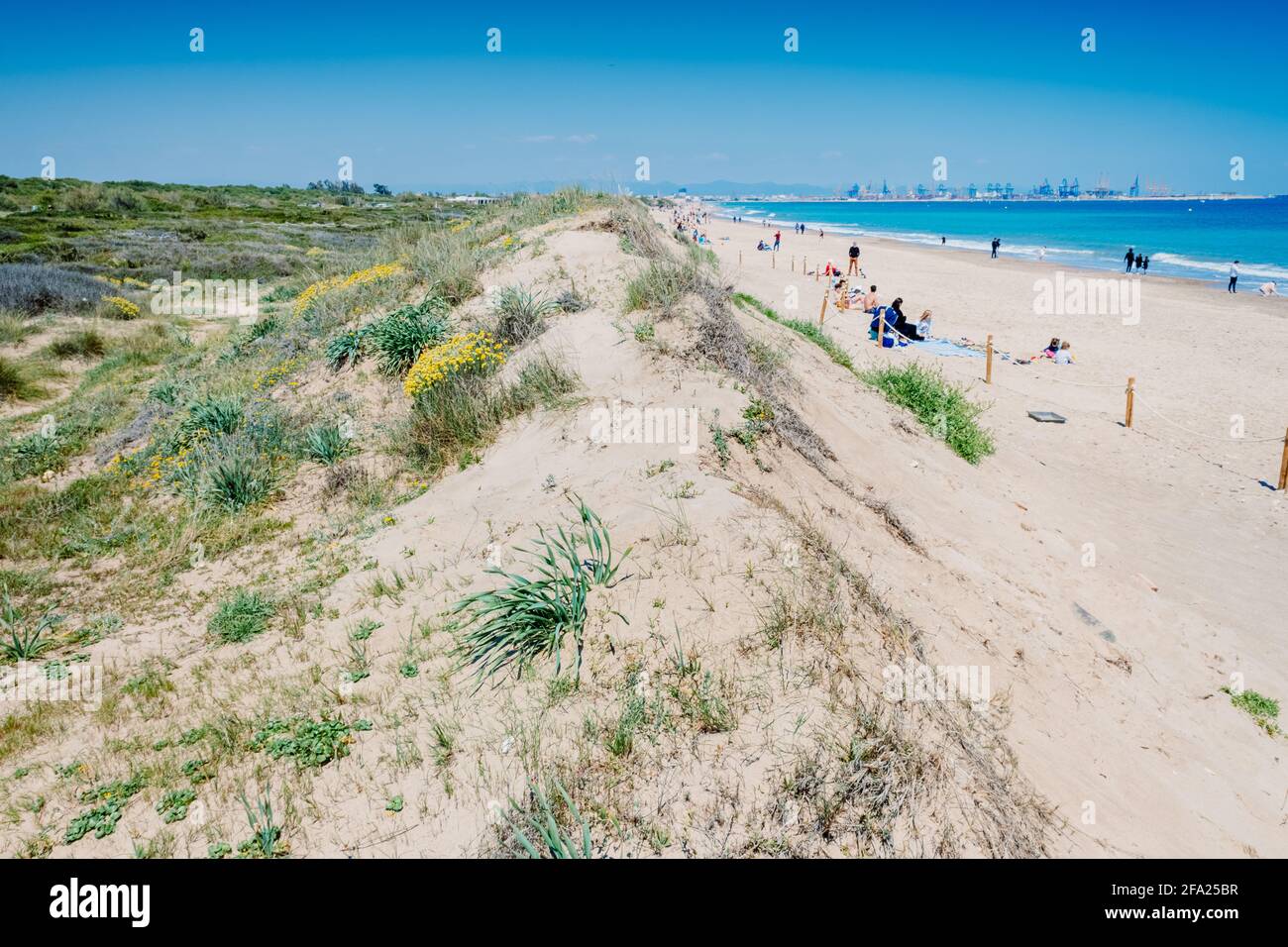 Valencia, Spain - April 21, 2021: Vacationers on a beach, next to the dunes of a protected natural area in El Saler. Stock Photo