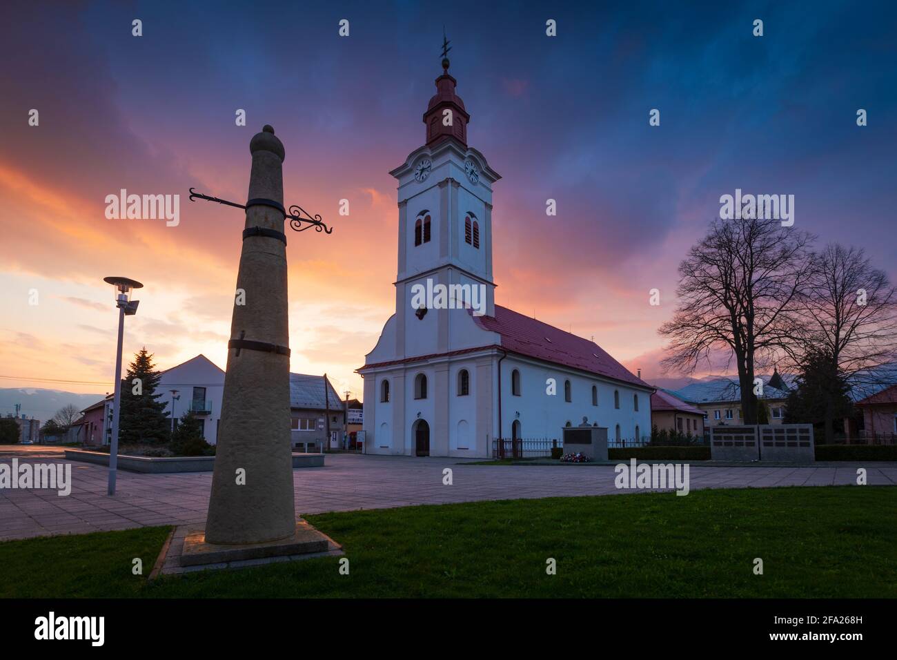 Church and whipping post in the main square of Sucany, Slovakia. Stock Photo