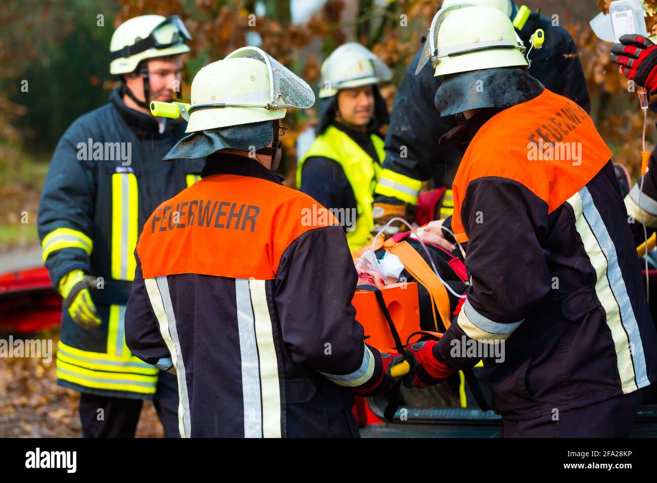 Accident - Fire brigade and Rescue team pulling cart with wounded person wearing a neck brace and respirator Stock Photo