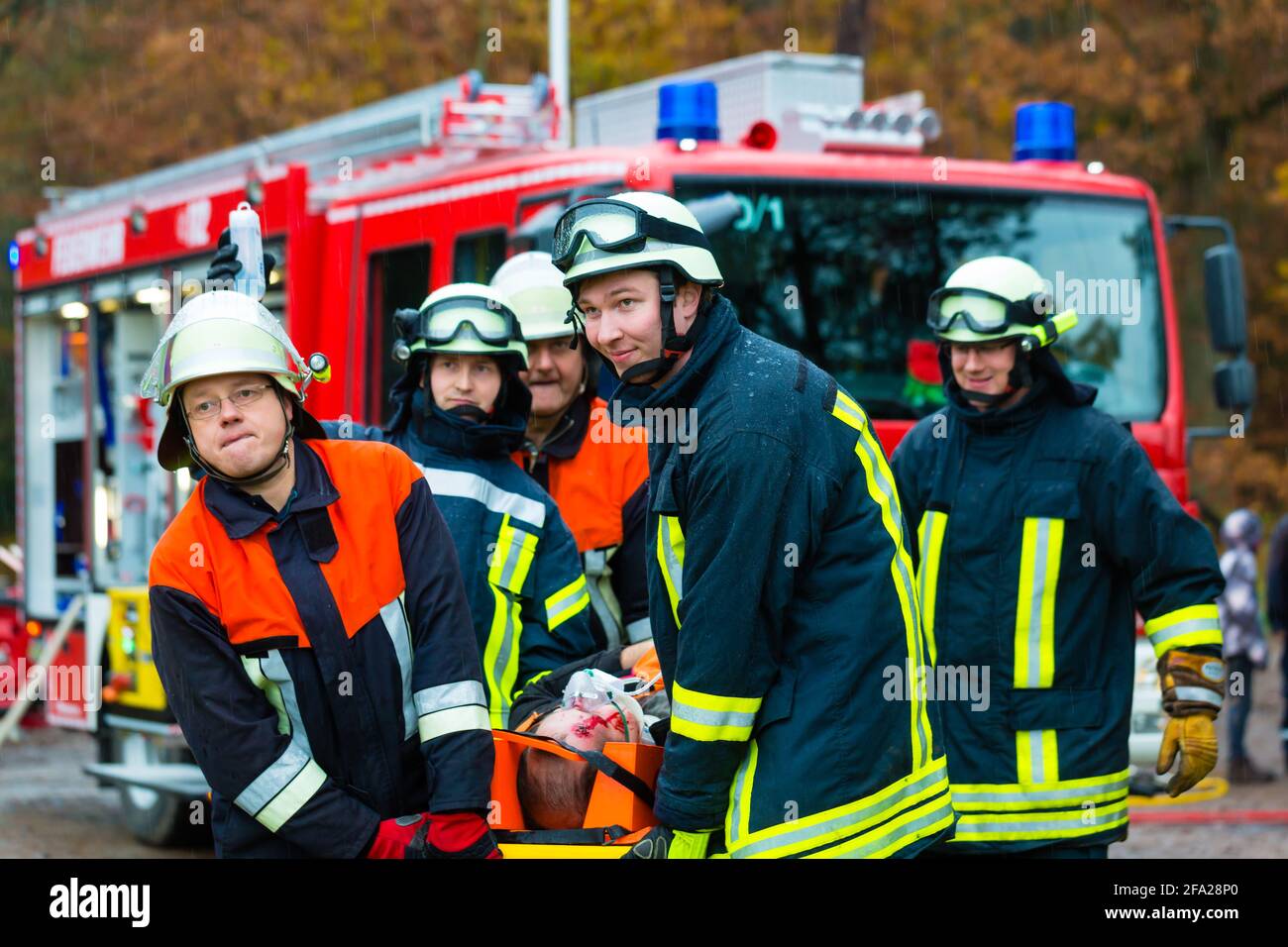 Accident - Fire brigade and Rescue team pulling cart with wounded person wearing a neck brace and respirator Stock Photo