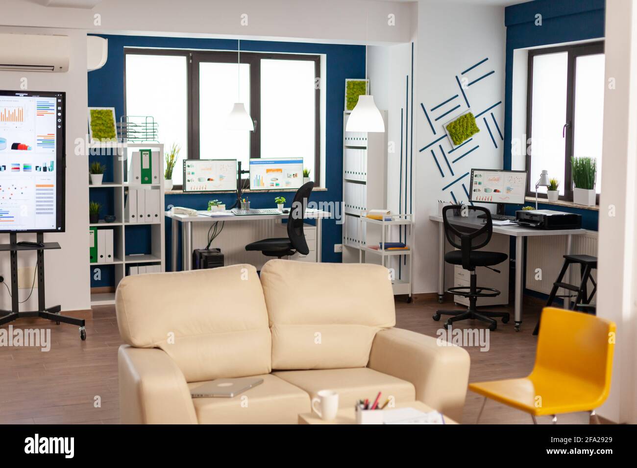 Interior of empty creative office with dusky light, new business, start up company with no people in it. Modern design and confortable couch with nobody in it, place of work startup Stock Photo