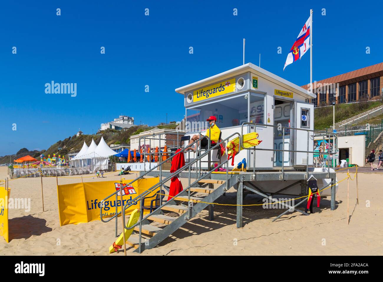 Bournemouth, Dorset UK. 22nd April 2021. UK weather: lovely warm and sunny in sheltered spots, but with a cool breeze; plenty of sunshine and blue skies at Bournemouth beaches, as few visitors head to the seaside to enjoy the sunshine. RNLI Lifeguard at Lifeguards kiosk hut keeps a look out. Credit: Carolyn Jenkins/Alamy Live News Stock Photo