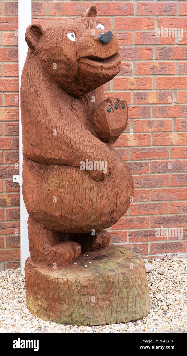 A welcoming, wooden, smiley bear in front garden on housing estate in Westbury, Wiltshire, England, UK. Stock Photo