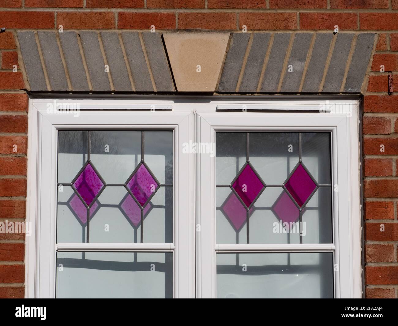 Coloured, patterned glass in window panes throwing shadows on the blinds behind. In Westbury, Wiltshire, England, UK. Stock Photo