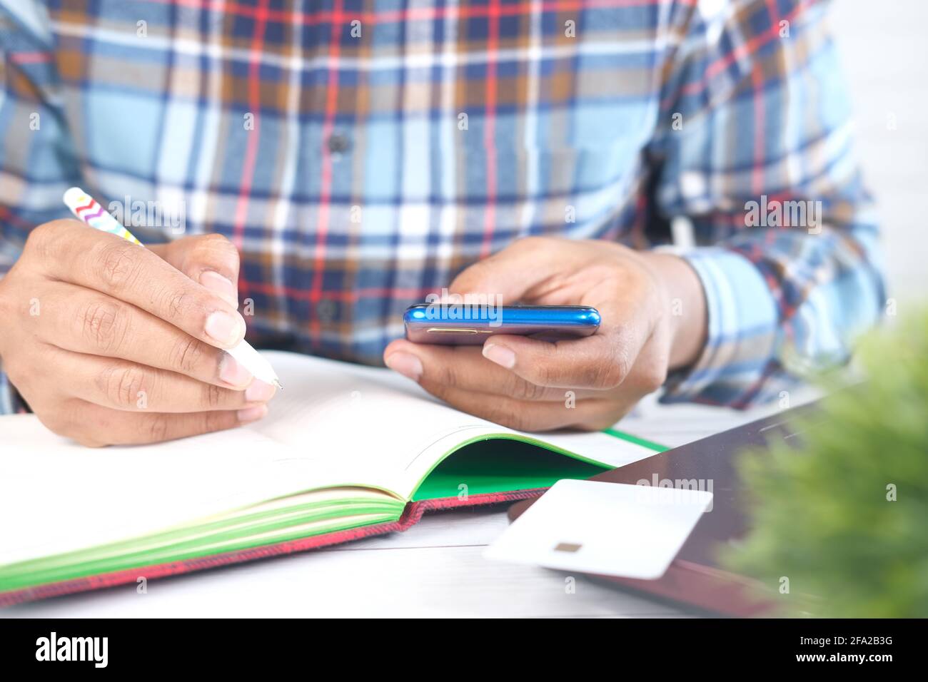 young man hand using smart phone and writing on notepad  Stock Photo