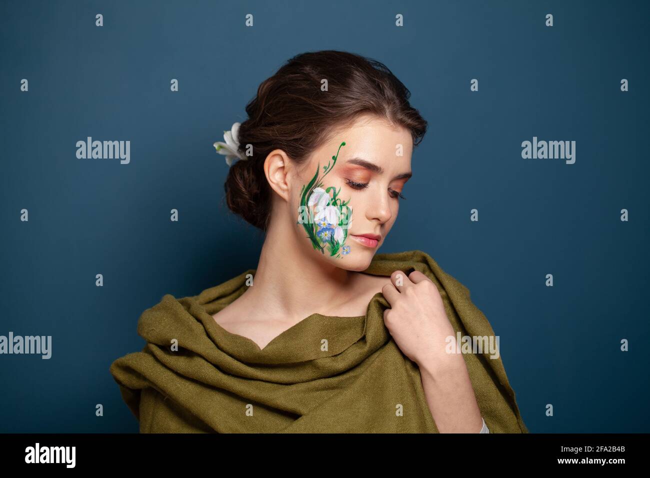 Perfect woman with painted flowers on her face on blue background Stock Photo