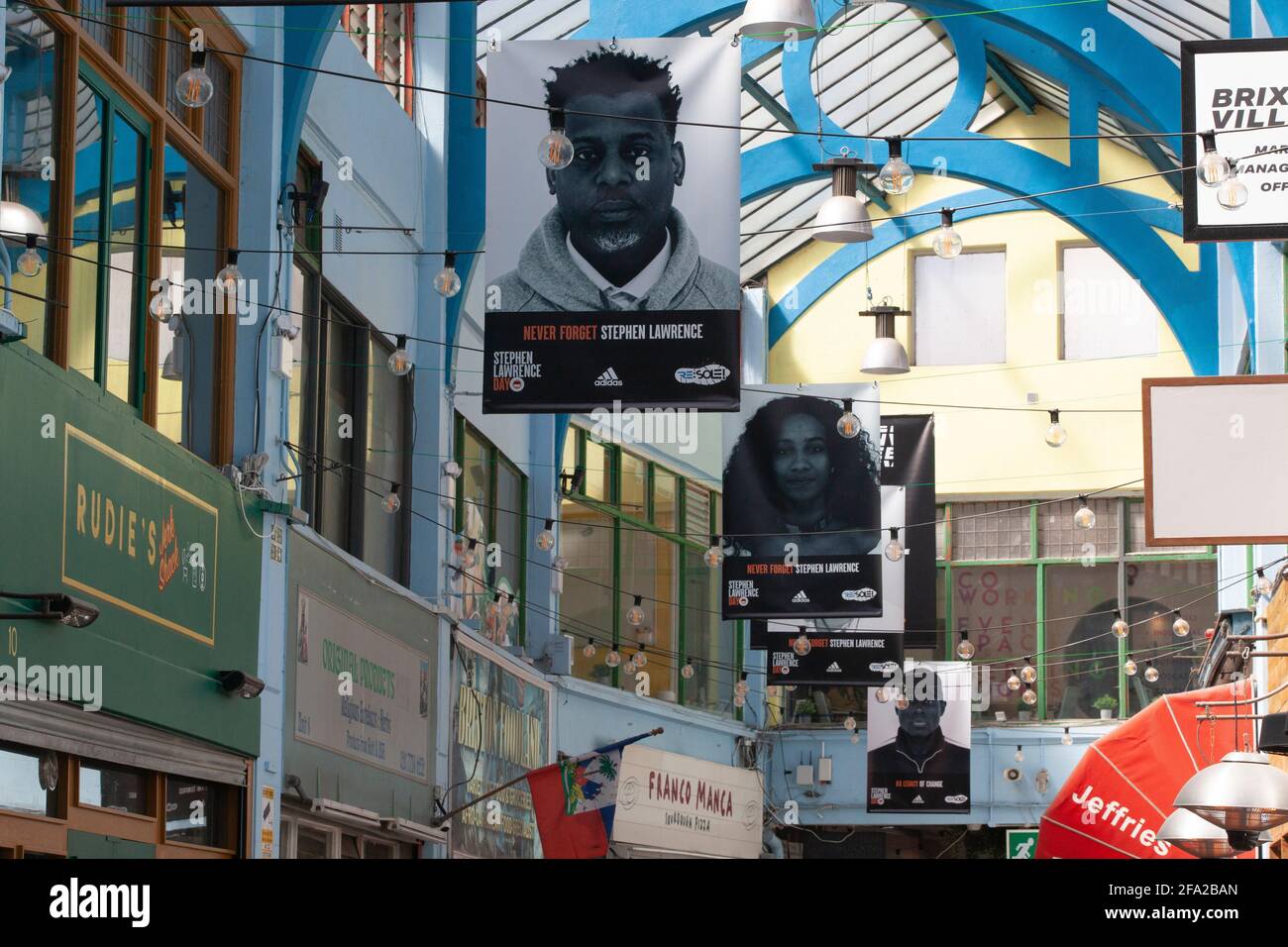 London, UK. 22nd Apr, 2021. On the anniversary of the murder of Stephen Lawrence in 1993, the Stephen Lawrence Day Foundation has banners up in the shopping arcades of Brixton Village with the hashtag #LegacyofChange. The charity works in classroom to encourage attainment in children, does community support work and helps marginalised young people access careers in honour of Stephen's aspiration to become an architect. Credit: Anna Watson/Alamy Live News Stock Photo